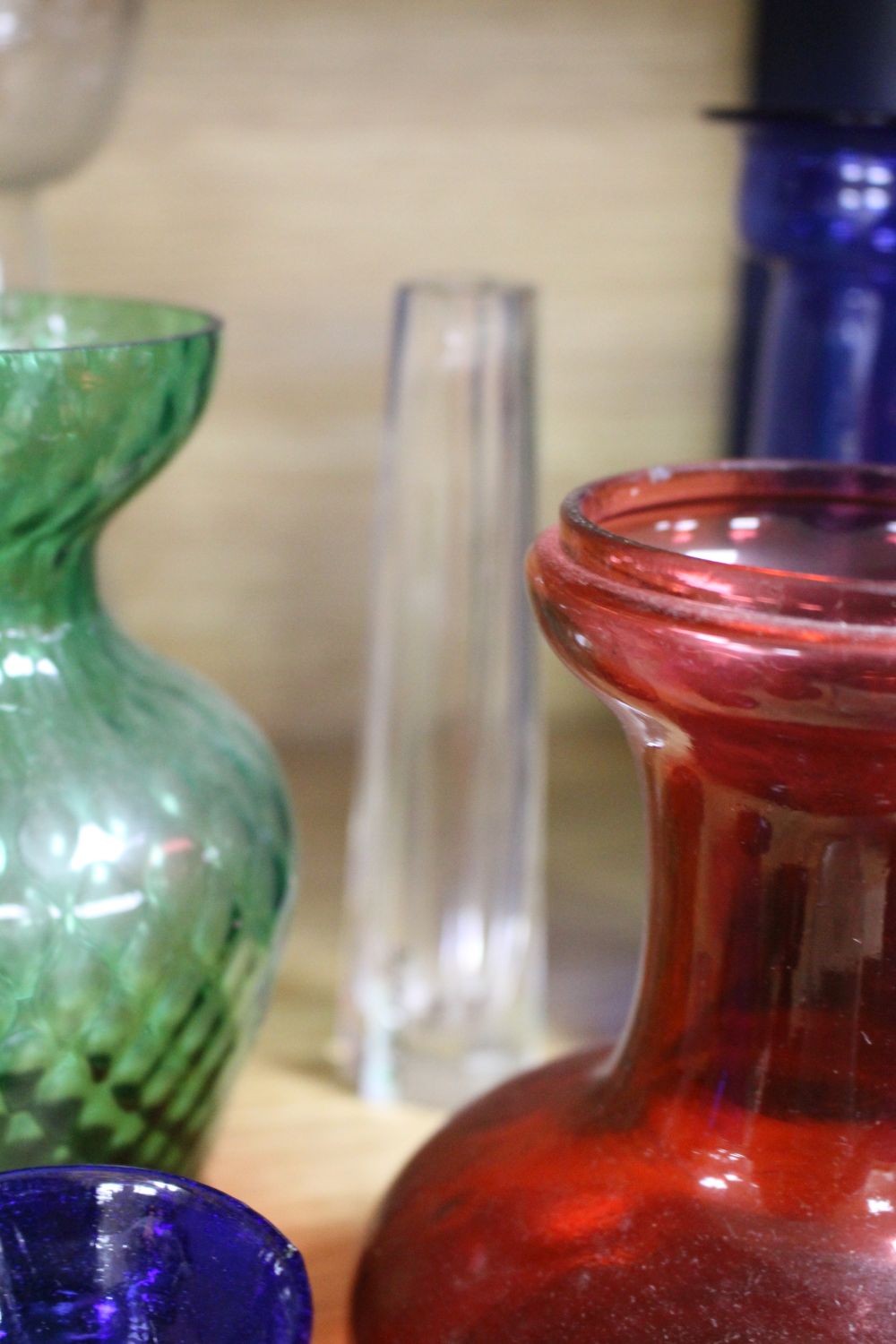A collection of assorted coloured glassware including hyacinth vases, tallest 21cm